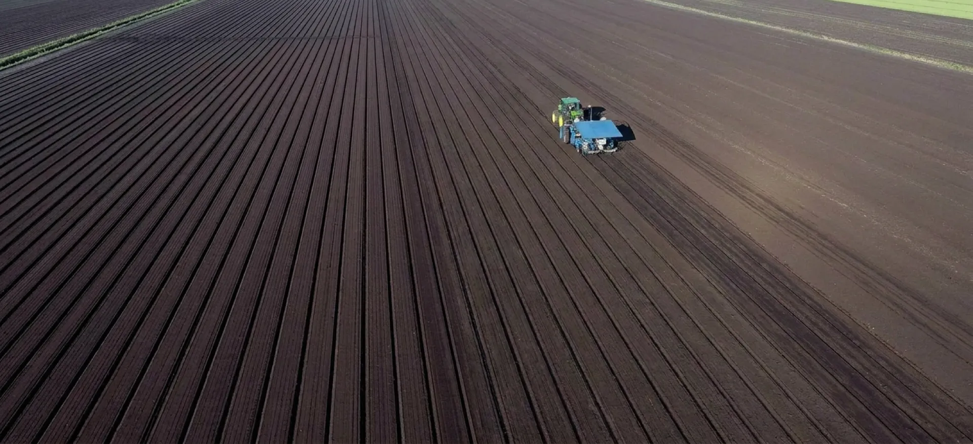 Aerial view of a Hundley Farms tractor working the rich plowed fields of South Florida